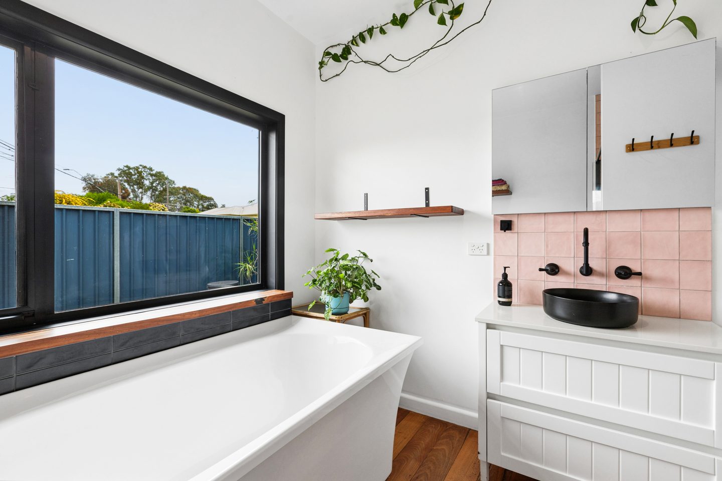 Bathroom with a freestanding bath, pink wall tiles and a black basin