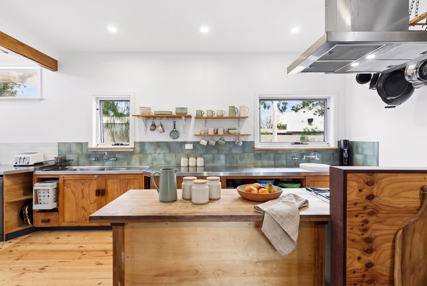 Kitchen with timber cabinetry and green tiled splashback